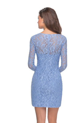 A woman with long brown hair is wearing the La Femme 28232 Long Sleeve Mini Lace Hoco Dress in light blue, fitted and long-sleeved, standing with her back to the camera.