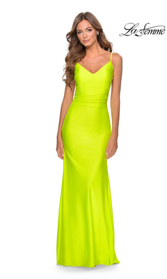 A woman models the La Femme Backless Long V-Neck Prom Dress 28287 in neon yellow with thin straps, standing before a white backdrop. The "La Femme" logo appears in the top right corner.