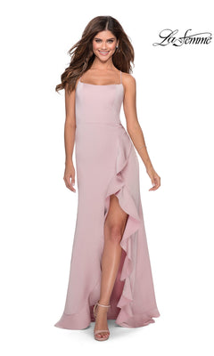 A woman models the La Femme Side-Ruffle Long Prom Dress 28294 in light pink, featuring thin straps, an open back, and a ruffled slit, paired with nude heels. The La Femme logo is displayed in the top right corner.