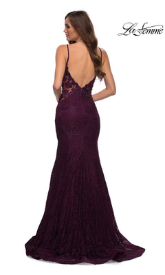 A woman stands facing away, wearing the La Femme Backless Long Lace Prom Dress 28355—a dark purple, floor-length mermaid gown with lace fabric, open back, and spaghetti straps.