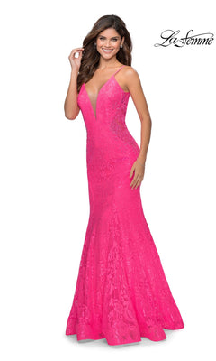 A woman in the La Femme Backless Long Lace Prom Dress 28355, featuring bright pink lace, thin straps, a deep V-neckline, and a mermaid skirt, smiles against a white background.