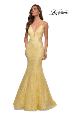 A woman models the La Femme Backless Long Lace Prom Dress 28355 in yellow, featuring a mermaid skirt, deep V neckline, and thin straps, standing against a white background.
