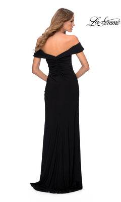 Woman models the La Femme Off-the-Shoulder Long Prom Dress 28389, a floor-length black gown with ruched details, shown from the back against a white background. "La Femme" appears in the top right corner.