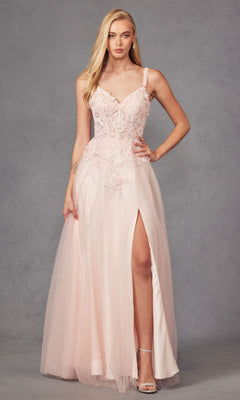 A woman stands against a gray backdrop wearing the Long Prom Dress 283 by Juliet—a light pink, beaded A-line gown with spaghetti straps, lace embroidery, and a thigh-high slit.