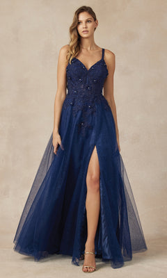 A woman wearing the Long Prom Dress 283 by Juliet—a sleeveless, navy blue, floor-length A-line gown with a v-neckline, floral embellishments, lace embroidery, and a thigh-high slit—stands against a neutral background.