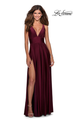 A woman stands smiling against a white background, wearing the La Femme Deep V-Neck Long A-Line Prom Dress 28547 in burgundy, featuring a sleeveless design and high slit. The "La Femme" logo appears at the top right of this elegant scene.