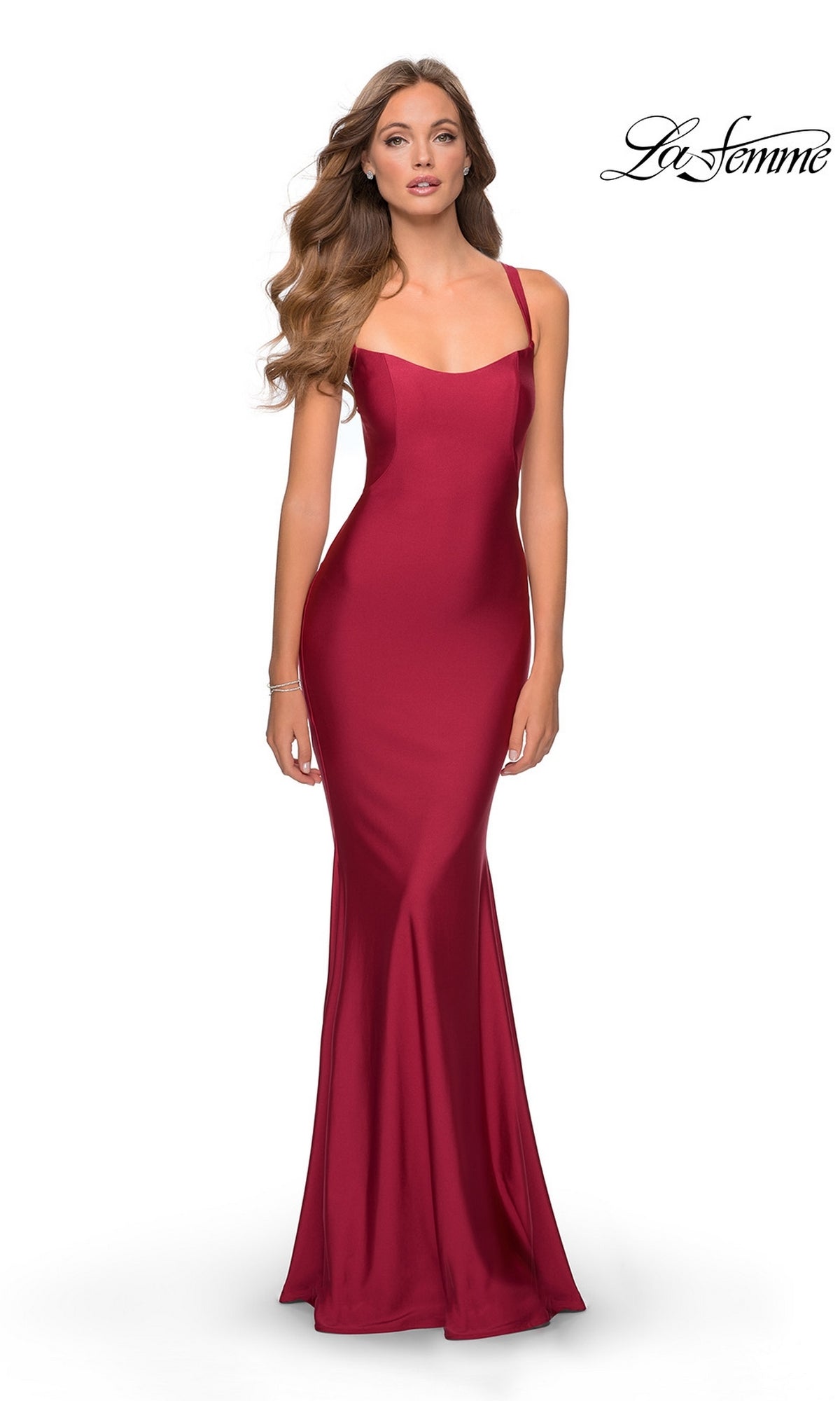A woman models the La Femme Simple Long Prom Dress 28568 in burgundy—a fitted, floor-length, sleeveless gown with thin straps and an open back—against a white background. The 