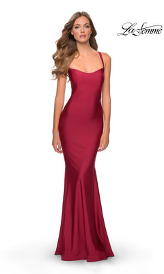 A woman models the La Femme Simple Long Prom Dress 28568 in burgundy—a fitted, floor-length, sleeveless gown with thin straps and an open back—against a white background. The "La Femme" logo is in the top right corner. Ideal for formal events.