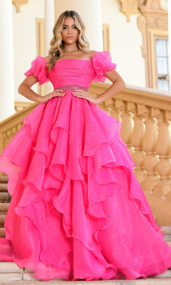 A woman stands on stairs in a bright pink Puff-Sleeve Long Prom Ball Gown (Ava Presley 28571) with ruffles and a jeweled belt, styled for elegance, with a classical building as the backdrop.
