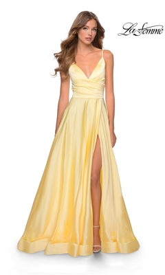 A woman wears the La Femme V-Neck Long A-Line Prom Dress 28607 in pale yellow with a deep V-neckline, thin straps, and a high slit, standing against a white background. The "La Femme" logo is in the top right corner.
