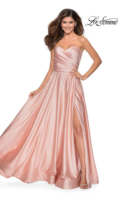 Woman in the La Femme Strapless Long A-Line Prom Dress 28608, featuring a blush pink satin fabric, strapless sweetheart neckline, and high slit, stands smiling.