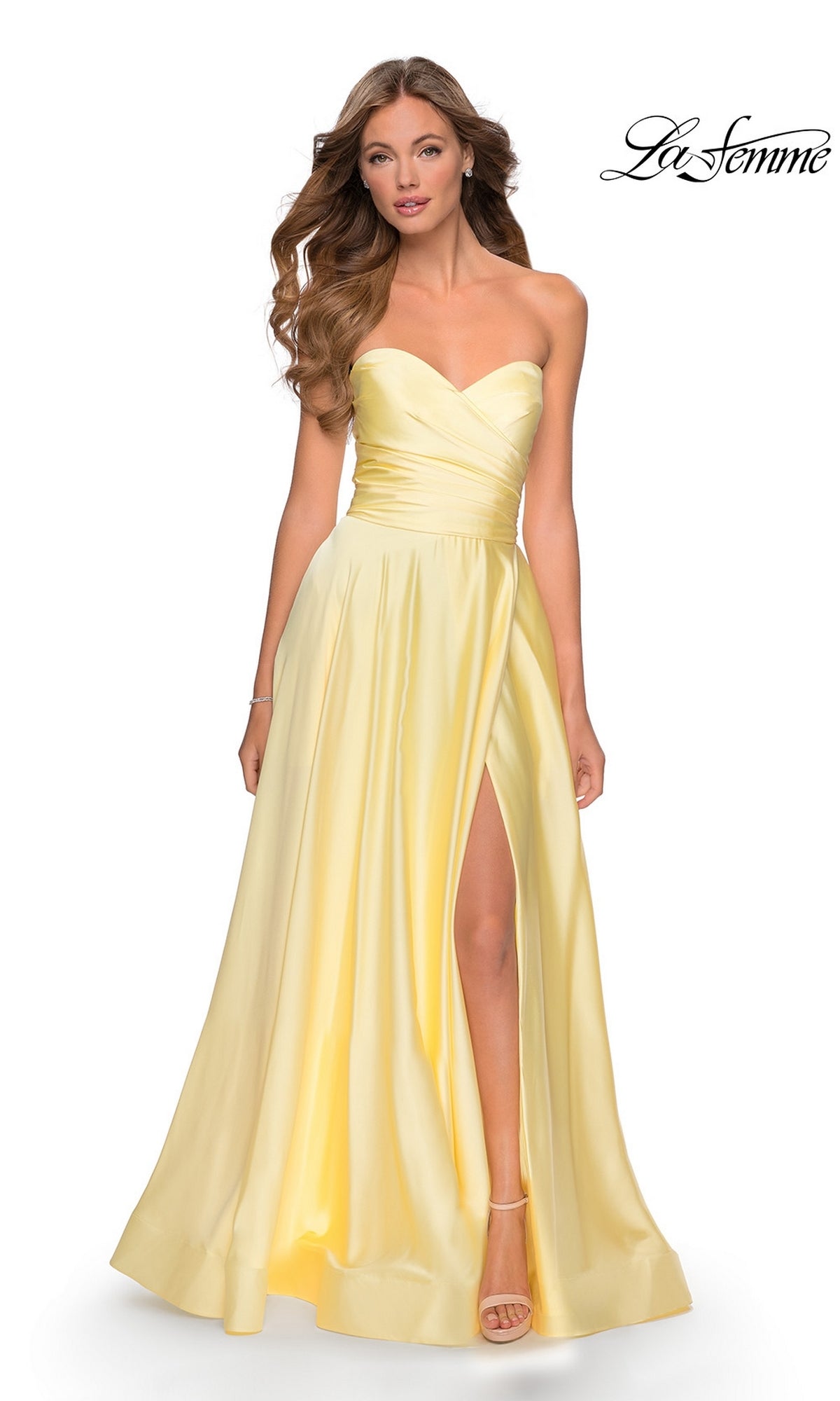 A woman wears the La Femme Strapless Long A-Line Prom Dress 28608 in pale yellow, featuring a strapless sweetheart neckline and high slit, as she stands against a plain white background.
