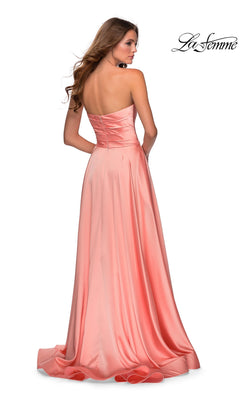 A woman faces away from the camera in a light pink satin La Femme Strapless Long A-Line Prom Dress 28608, featuring a sweetheart neckline and slight train. The La Femme logo is visible in the upper right corner.