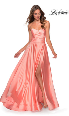 A woman wears the La Femme Strapless Long A-Line Prom Dress 28608 in peach satin, featuring a strapless sweetheart neckline and high slit, standing against a white background.