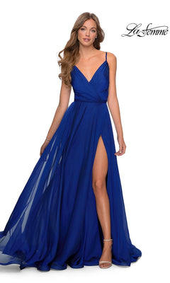 A woman wearing a marine blue Long Prom Dress: La Femme 28611, a floor-length gown with a pleated surplice bodice, spaghetti straps, and an A-line skirt featuring a high leg slit.
