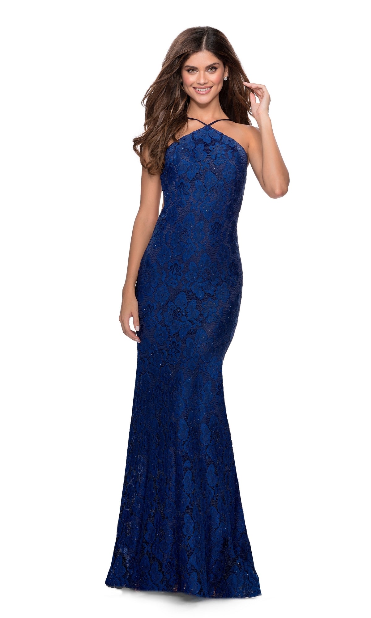 A woman stands and smiles in a floor-length, fitted La Femme 28619 prom dress—royal blue, sleeveless, high-necked, backless, with delicate floral lace.