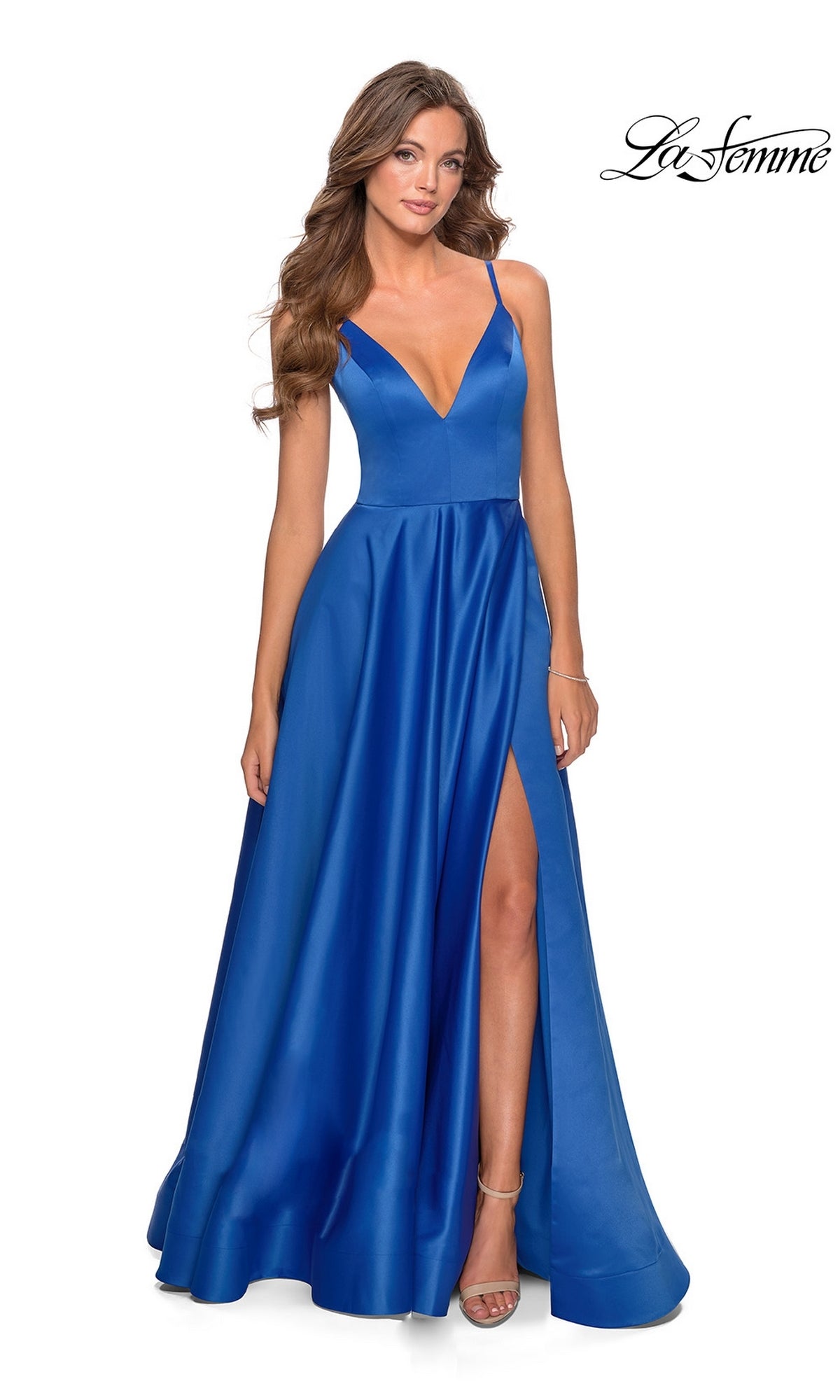 A woman stands against a white background wearing the royal blue La Femme Strappy-Back Long A-Line Prom Dress 28628, featuring thin straps, a deep V-neckline, and a high slit. The La Femme logo is in the top right corner.