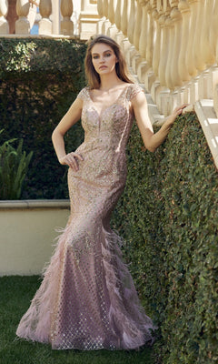 A woman poses outdoors against a stone railing and hedge, wearing the Feathered Cap-Sleeve Long Prom Dress: Juliet 286—a fitted, light pink mermaid gown with sequins and feather details.