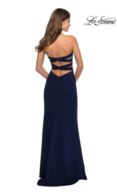 A woman in a La Femme Strappy-Back Long Strapless Prom Dress, navy blue and floor-length, featuring three horizontal back straps, stands facing away.
