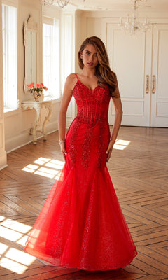 A woman wears the Juliet JT2883C, a fitted, sparkly red long mermaid glitter prom dress with thin straps, standing in a bright room with wooden floors and white walls.