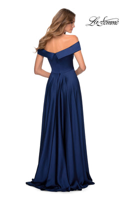 A woman is seen from the back in a navy blue La Femme Off-Shoulder Long A-Line Prom Dress 28978, featuring a fitted bodice and flowing floor-length skirt.