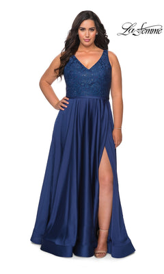 A woman wears a navy Long Plus-Size Prom Dress: La Femme 29004, a sleeveless floor-length satin A-line gown with a V-neck, rhinestone-embellished bodice, and high side slit.