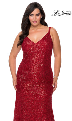 A woman wearing a floor-length, red sequined V-neck La Femme 29006 prom dress with spaghetti straps.