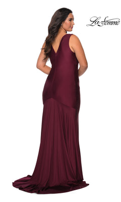 A woman wearing a La Femme 29016 long plus-size prom dress in floor-length burgundy jersey with a sleeveless, faux wrap-style V-neckline and a flared hem.