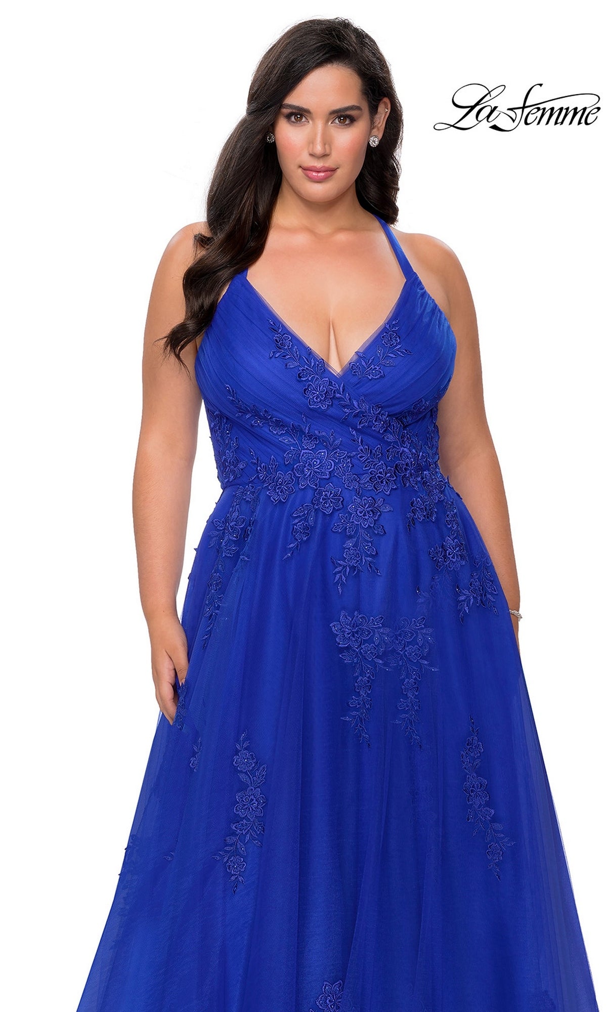 A woman wears the La Femme Long Prom Dress 29021, a royal blue sleeveless ball gown featuring floral embroidery and a deep V neckline, standing against a white background. The “La Femme” logo appears in the top right corner.