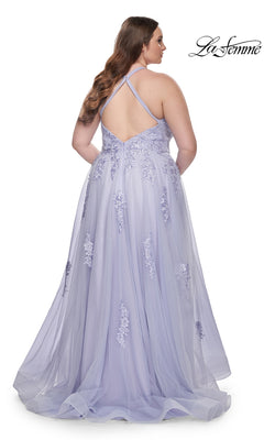A woman stands facing away from the camera in the La Femme Long Prom Dress 29021, featuring lavender fabric, floral embroidery, and a crisscross back.