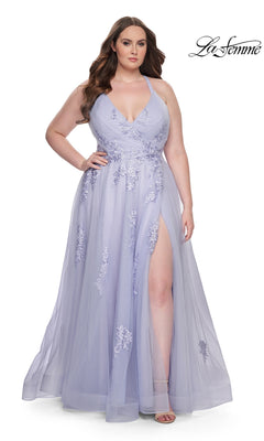 A woman stands against a white background wearing the La Femme Long Prom Dress 29021, a lavender sleeveless formal gown featuring floral embroidery, a deep V neckline, and a high slit.