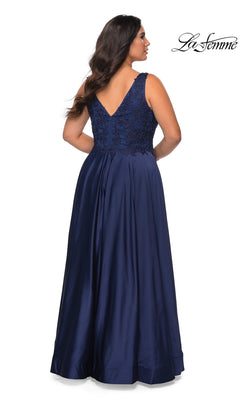 A woman seen from the back wearing a Long Plus-Size Prom Dress: La Femme 29039, a floor-length navy blue satin gown with a V-neckline and lace bodice detail.
