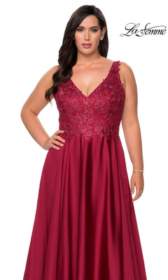 A plus-size woman wears the Long Plus-Size Prom Dress: La Femme 29039, a long, deep red formal gown with a V-neckline and a bodice featuring rhinestone lace and floral embroidery.