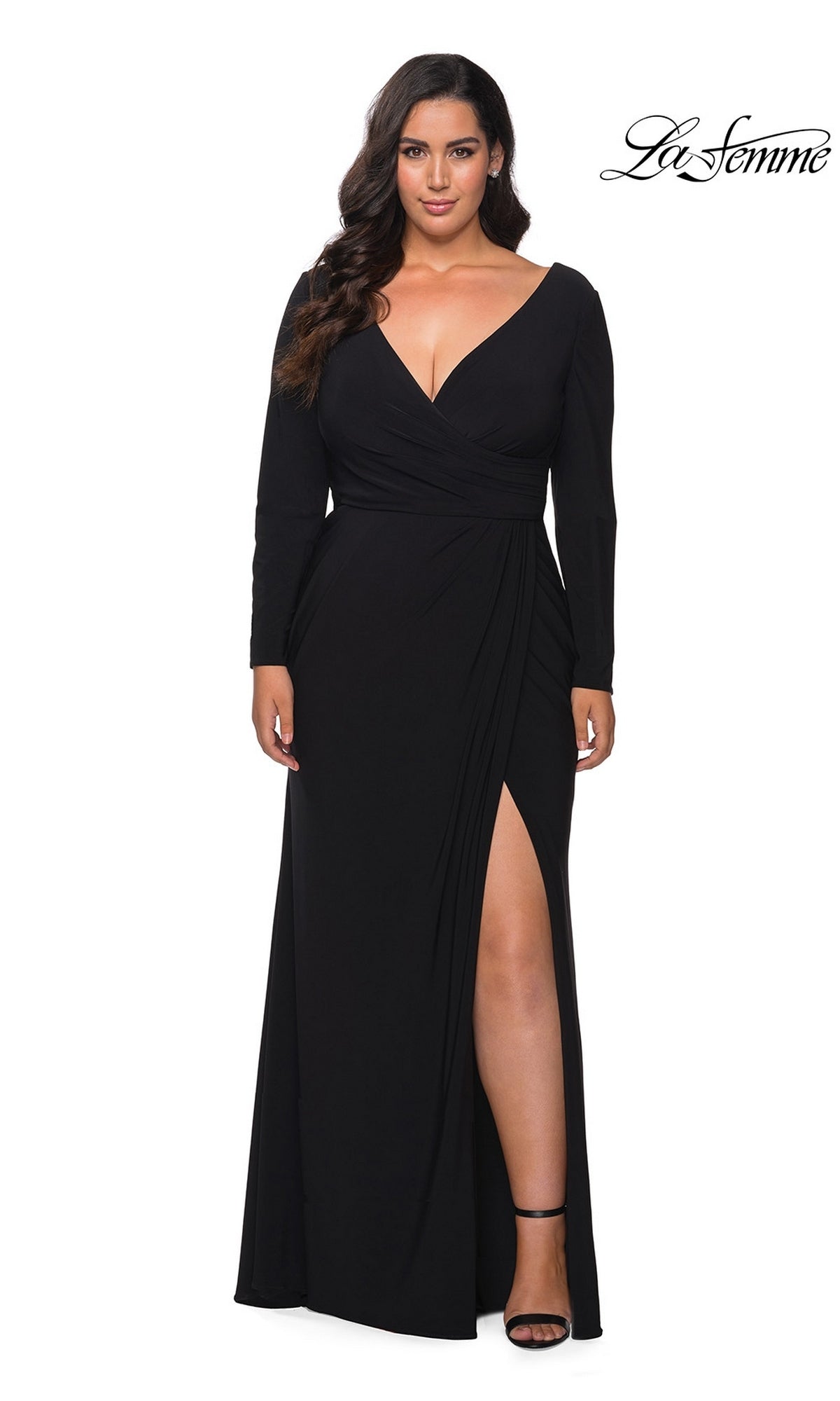 A woman wearing the black Long Plus-Size Prom Dress: La Femme 29044, featuring a long-sleeve faux wrap bodice, V-neckline, and a high side slit.