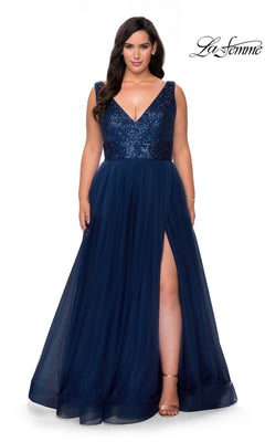 A woman wearing the Long Plus-Size Prom Dress: La Femme 29045 in navy with a sleeveless deep V-neck, sequin bodice, tulle A-line skirt, and high slit.