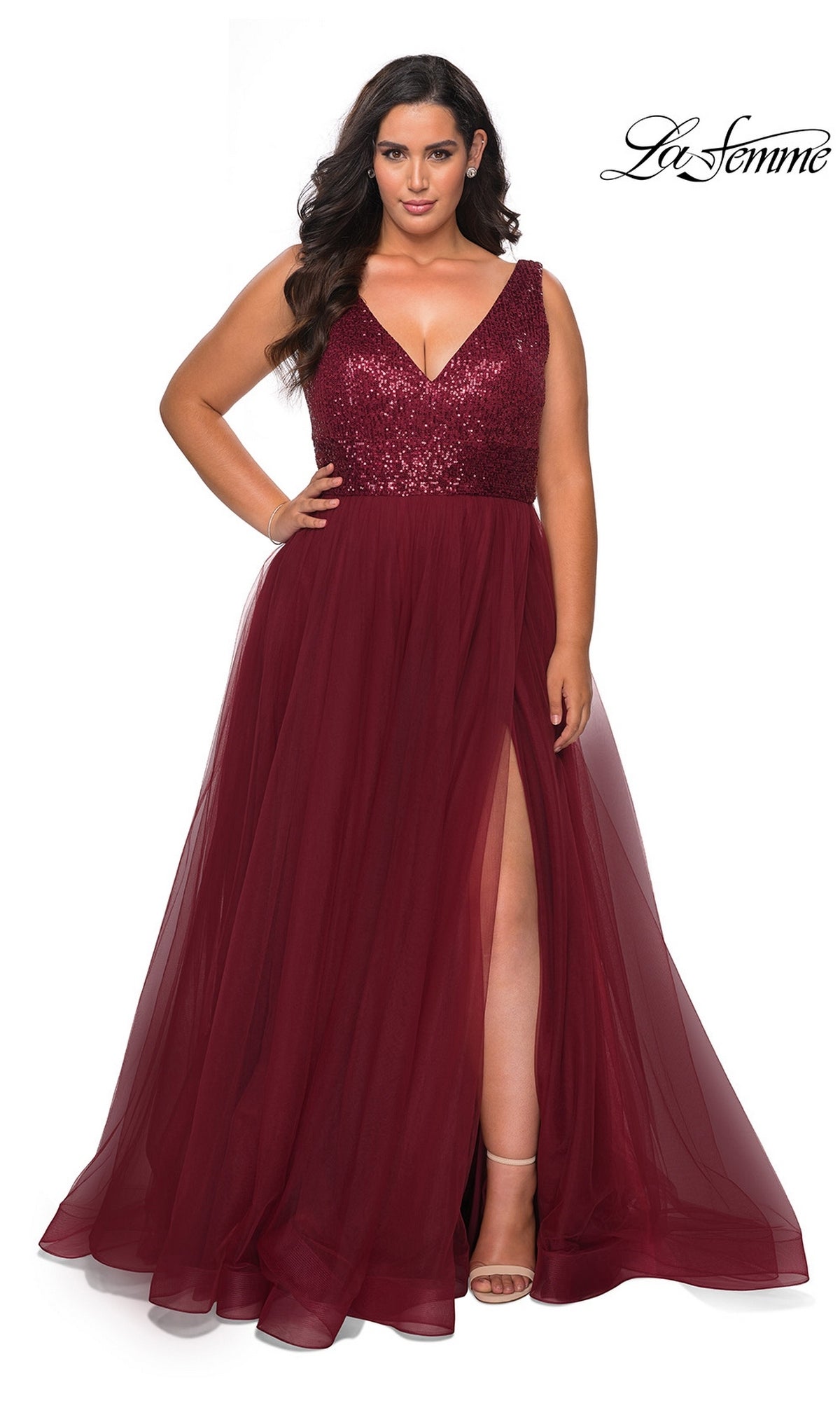 A woman wears the Long Plus-Size Prom Dress: La Femme 29045 in wine, featuring a sequin bodice, tulle A-line skirt, sleeveless style, and thigh-high slit. The La Femme logo is top right.