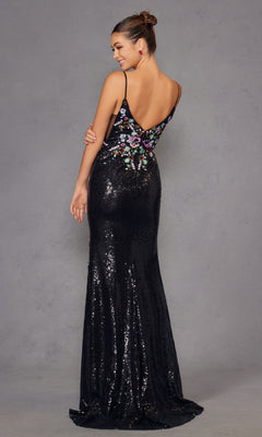 A woman poses in the Juliet JT2909K, a long black sequin prom gown with colorful floral embroidery and a low back, against a plain gray background.