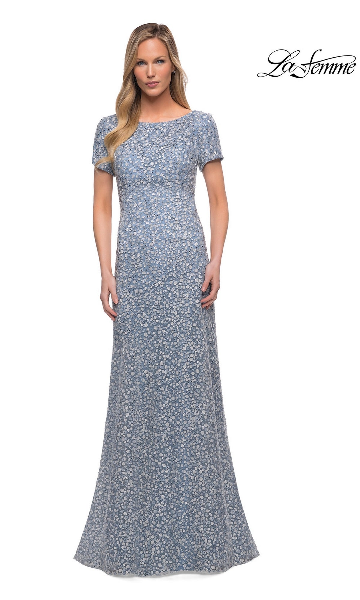 A woman models the Long Formal Dress: La Femme 29134, a modest, light blue floral sheath gown, standing against a plain white background with the “La Femme” logo top right.