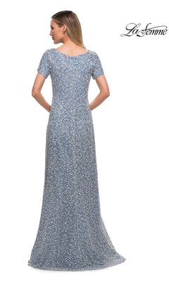 A woman faces away in the Long Formal Dress: La Femme 29134—a blue lace sheath gown with a subtle floral pattern. The La Femme logo appears in the top right corner.