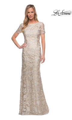 Woman wearing an elegant La Femme 29161 long formal dress—a floor-length, short-sleeve beige lace sheath evening gown adorned with delicate floral patterns; “La Femme” logo in the top right corner.