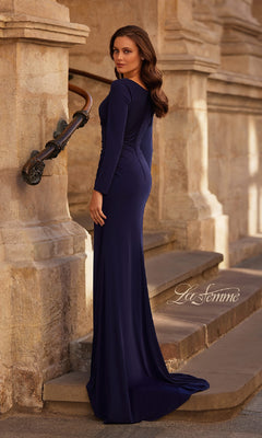 A woman wearing the La Femme 29184 Long Sleeve Long Formal Dress stands on stone steps, glancing over her shoulder with loose waves in her hair.
