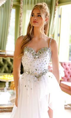 A woman in a white, strapless Ava Presley 29189 Tiered Long Prom Ball Gown with silver embellishments stands indoors, with green chairs and a pink sofa in the background.