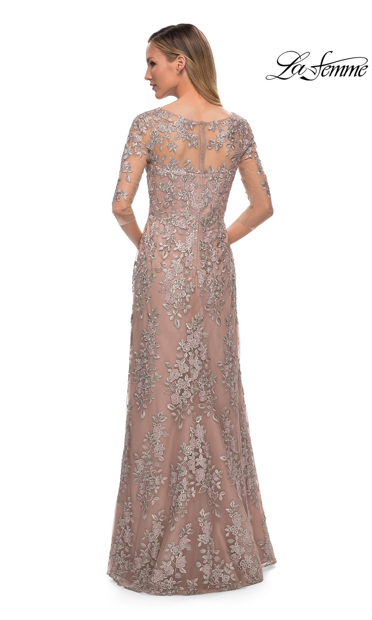 Woman in La Femme 29225, a floor-length blush pink formal dress with silver floral embroidery and sheer sleeves, seen from behind.