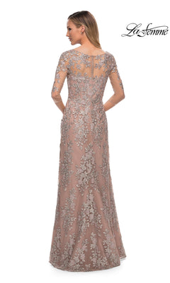 Woman in La Femme 29225, a floor-length blush pink formal dress with silver floral embroidery and sheer sleeves, seen from behind.