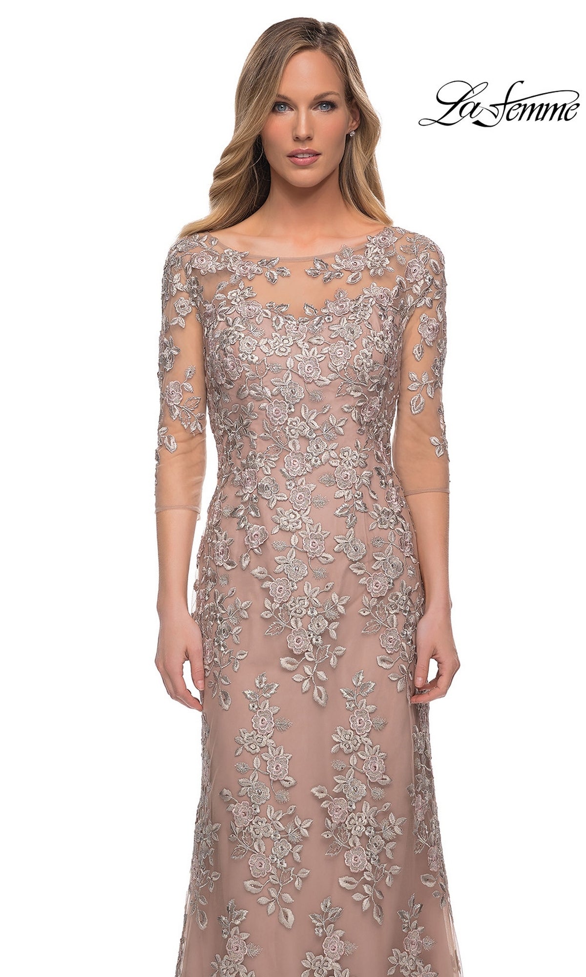 Woman wears the Long Formal Dress: La Femme 29225—floor-length blush pink with silver floral embroidery and sheer sleeves—against a white background.