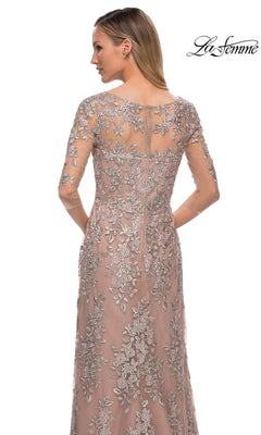 Woman wearing Long Formal Dress: La Femme 29225, a mauve sheath with silver floral embroidery and sheer sleeves; “La Femme” logo in the top right.