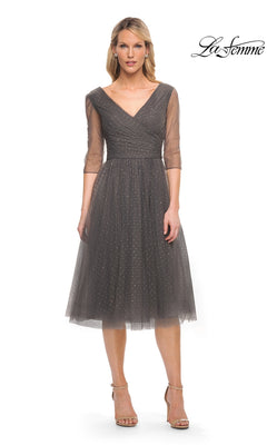 Woman in Knee Length Wedding Guest Dress: La Femme 29229 in gunmetal with sheer sleeves and sparkling v-neckline, white background, “La Femme” logo top right.