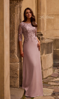 A woman in a Light Mauve Long Formal Dress: La Femme 29251 stands by a stone building, the rustic backdrop enhancing her elegant mother-of-the-bride style.