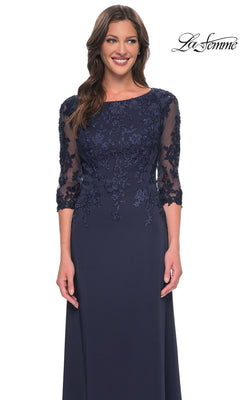 A woman models the Long Formal Dress: La Femme 29251 in navy blue, featuring lace embroidery and sheer three-quarter sleeves, smiling against a white background.