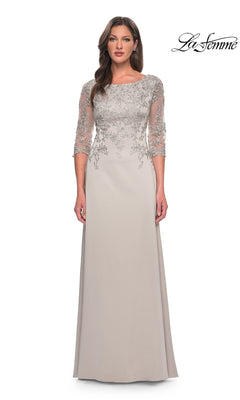 A woman wears a Long Formal Dress: La Femme 29251 in silver with lace, sheer embroidered sleeves, and a flowing skirt. La Femme logo appears in the corner.